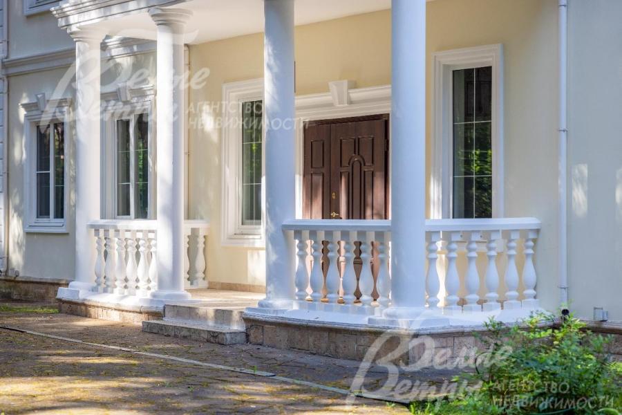 Дом в классическом стиле с колоннами, лепным декором и балюстрадами.