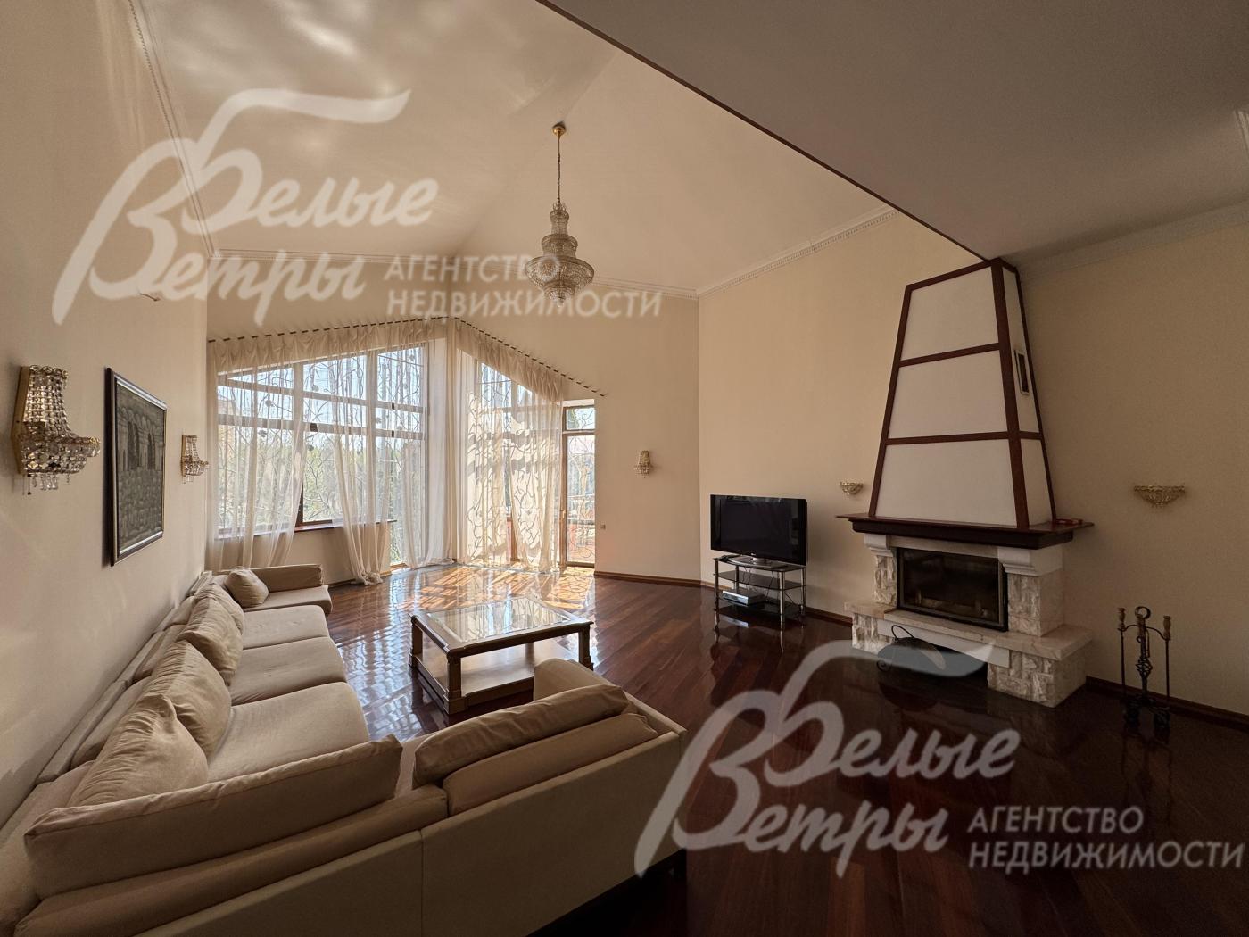 Атмосферу гостиной создают камин и стена с панорамным остеклением