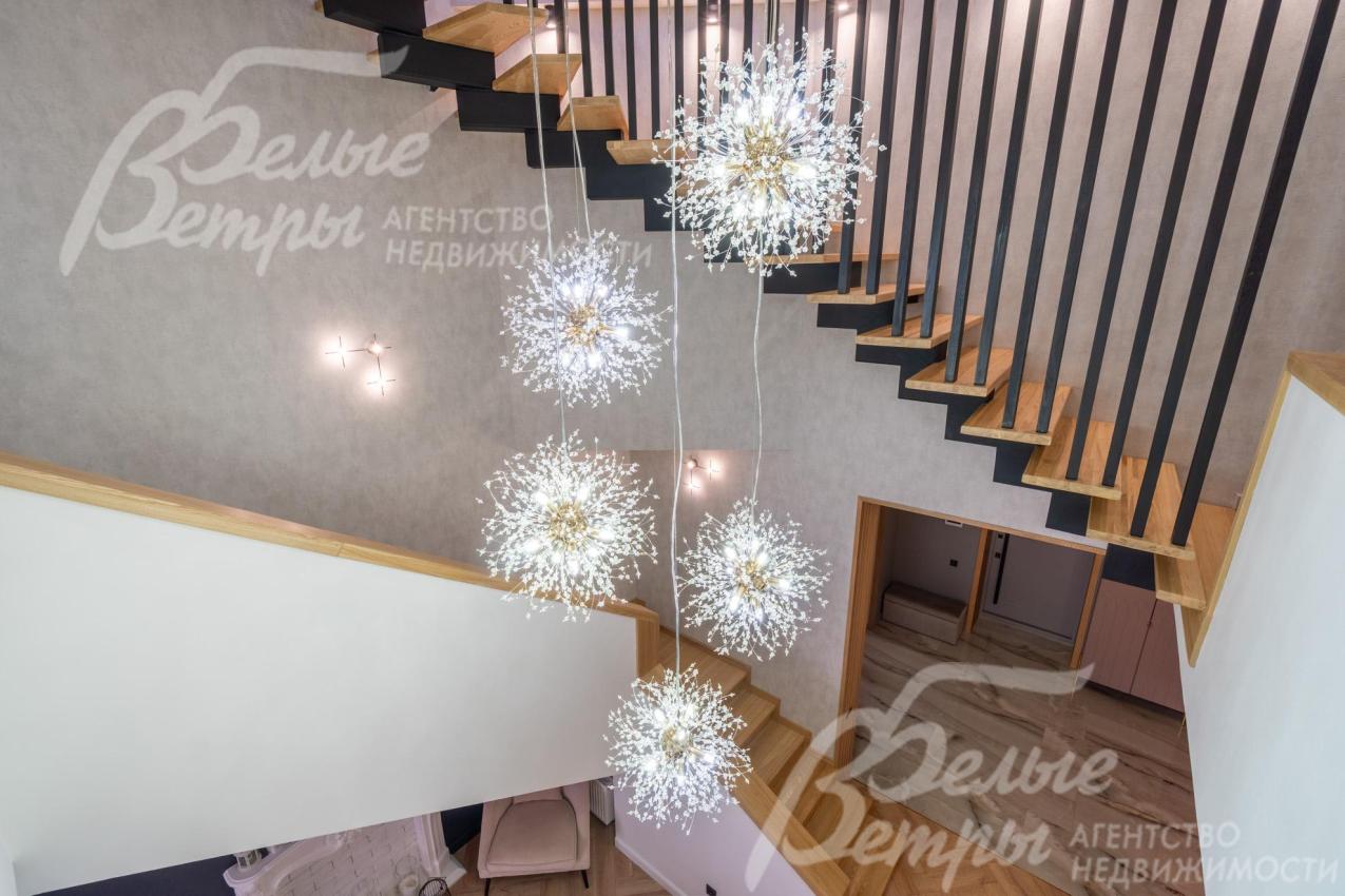 По центру над лестницей располагается эффектная подвесная люстра в стиле «одуванчик»