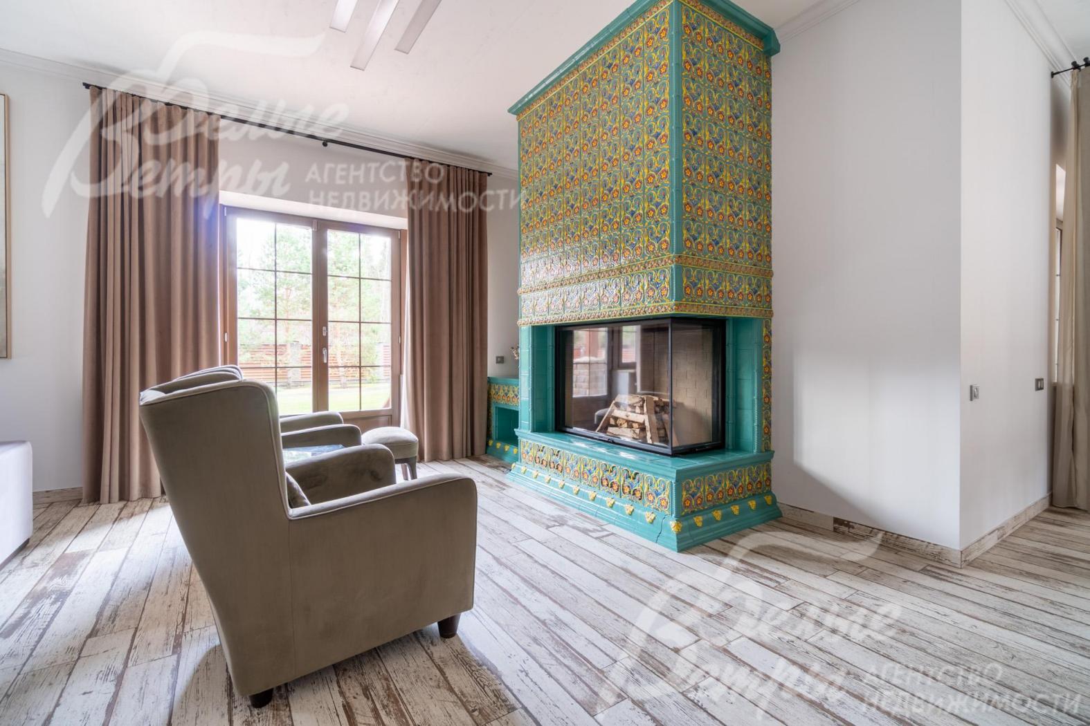 В гостиной - эксклюзивный камин гильотинного типа с двусторонней топкой и впечатляющим порталом до потолка: облицован фаянсовыми изразцами с ручной художественной росписью