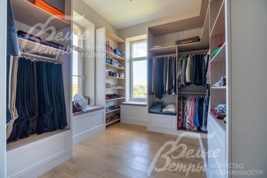 Гардеробная мастер-спальни с окнами и удобной системой хранения