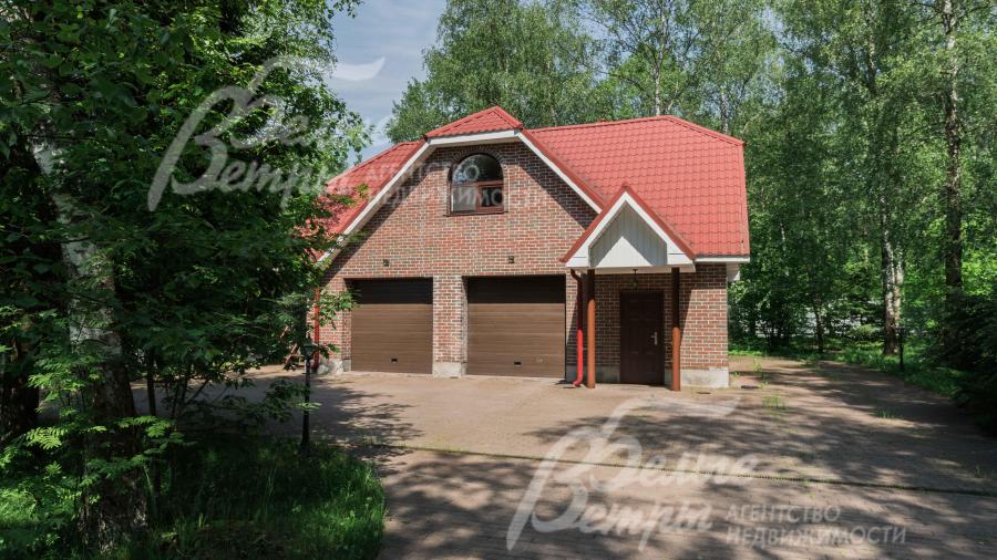 Вспомогательное 2-этажное строение в стиле основного дома с гаражом и квартирой для персонала, перед ним большая парковочная площадка 