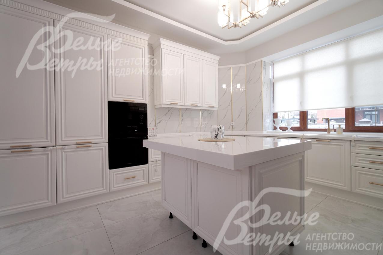 Белый гарнитур выполнен из массива ясеня, дополнен столешницей из искусственного камня, есть остров