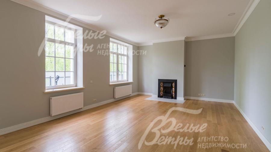 Гостиная площадью 40 кв.м с высокими потолками и со старинным  английским чугунным камином с изразцами