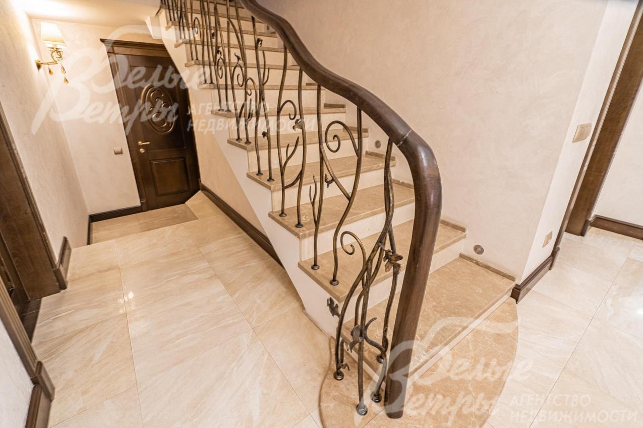 Лестница монолитная, отделана мрамором, с кованым ограждением и поручнем из дуба