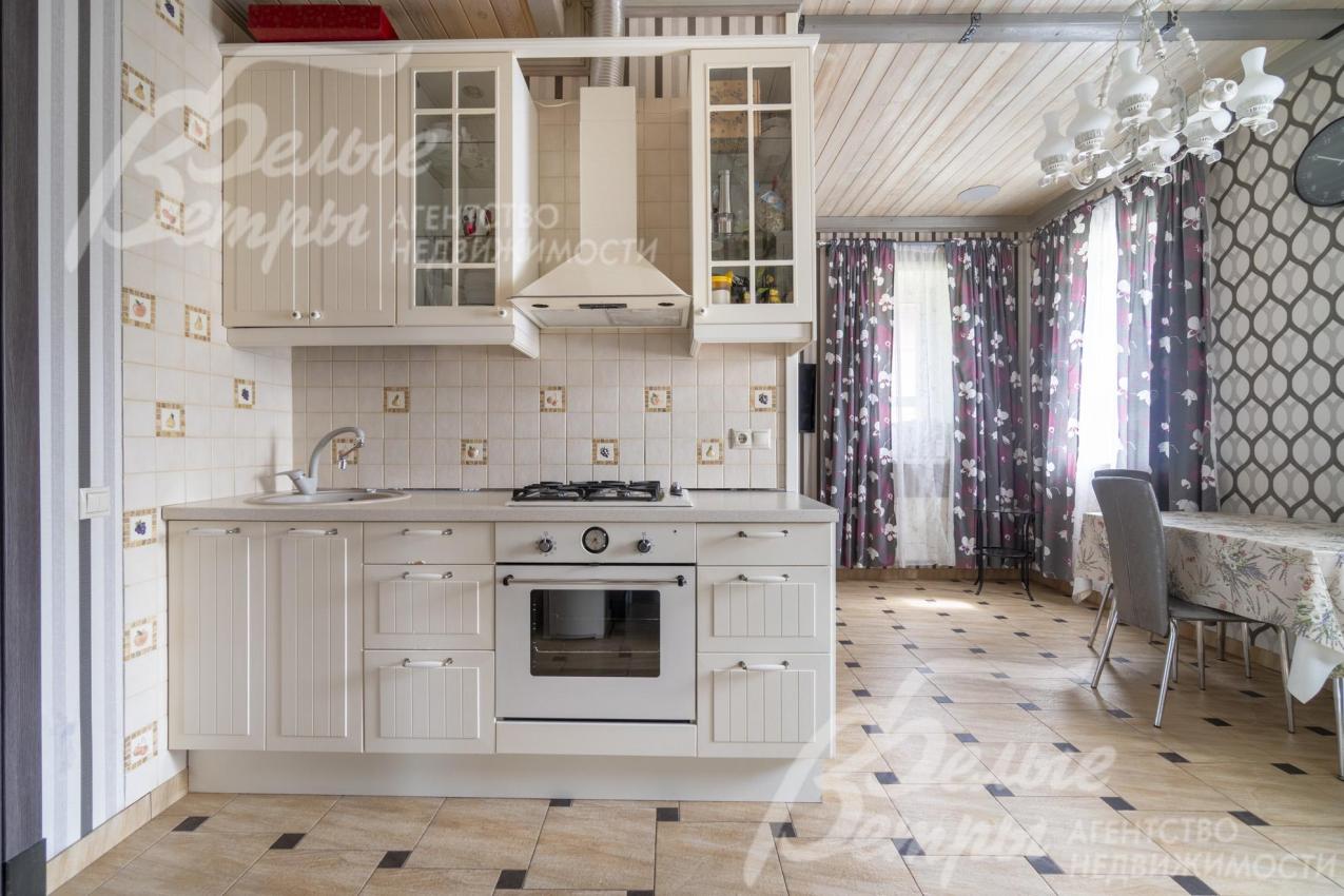 В кухне установлен белый кухонный гарнитур со всей необходимой техникой