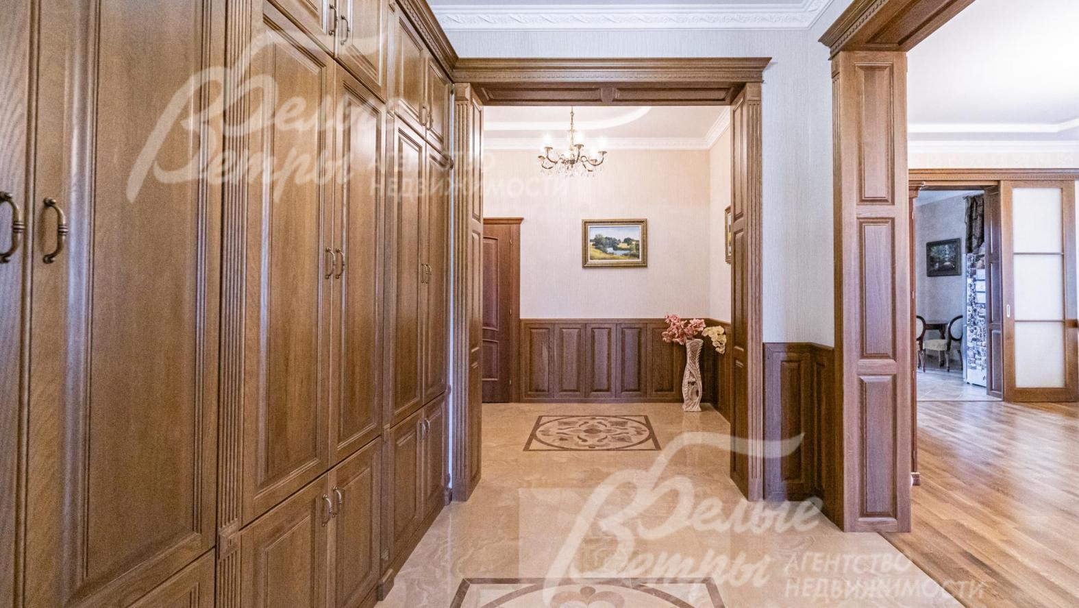 Холл со встроенными шкафами из массива. Таким же дерево отделаны высокие проемы