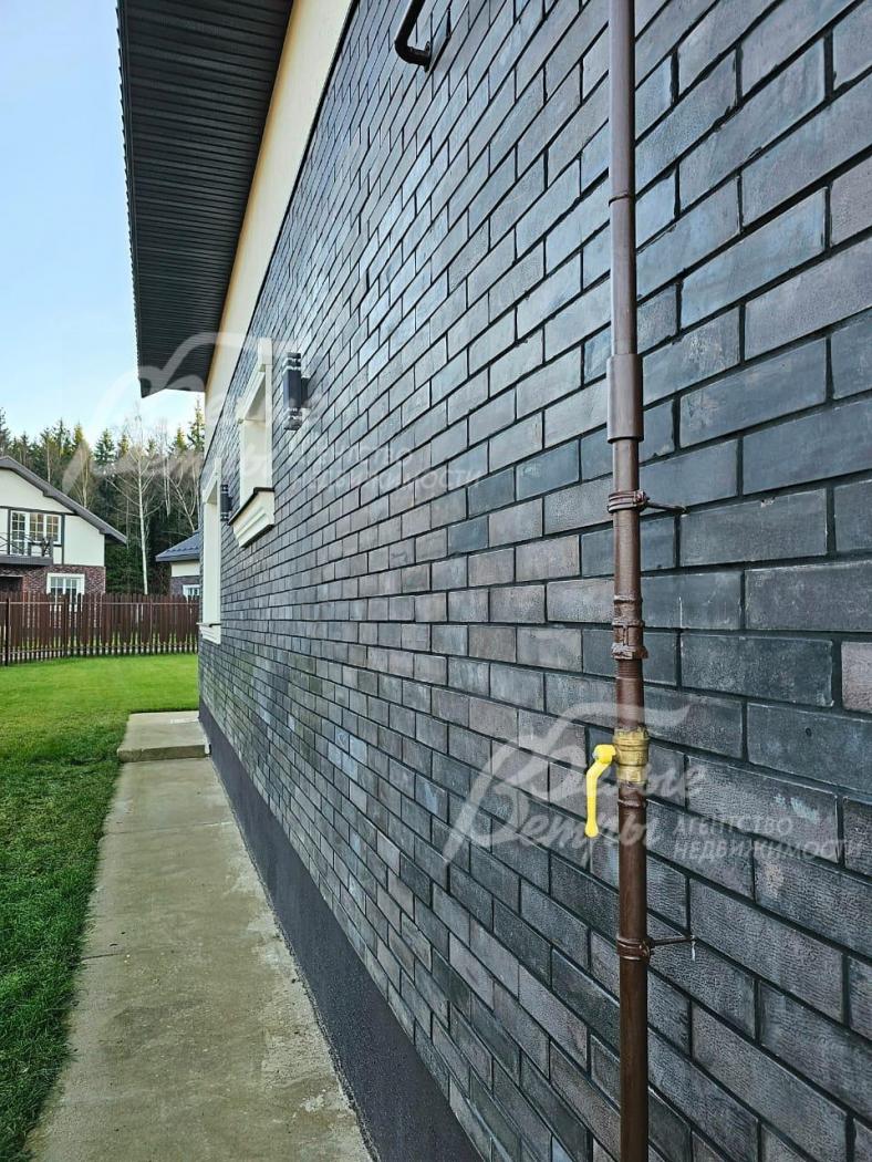 Стены 1го этажа облицованы термопанелями с темной плиткой под искусственный камень.