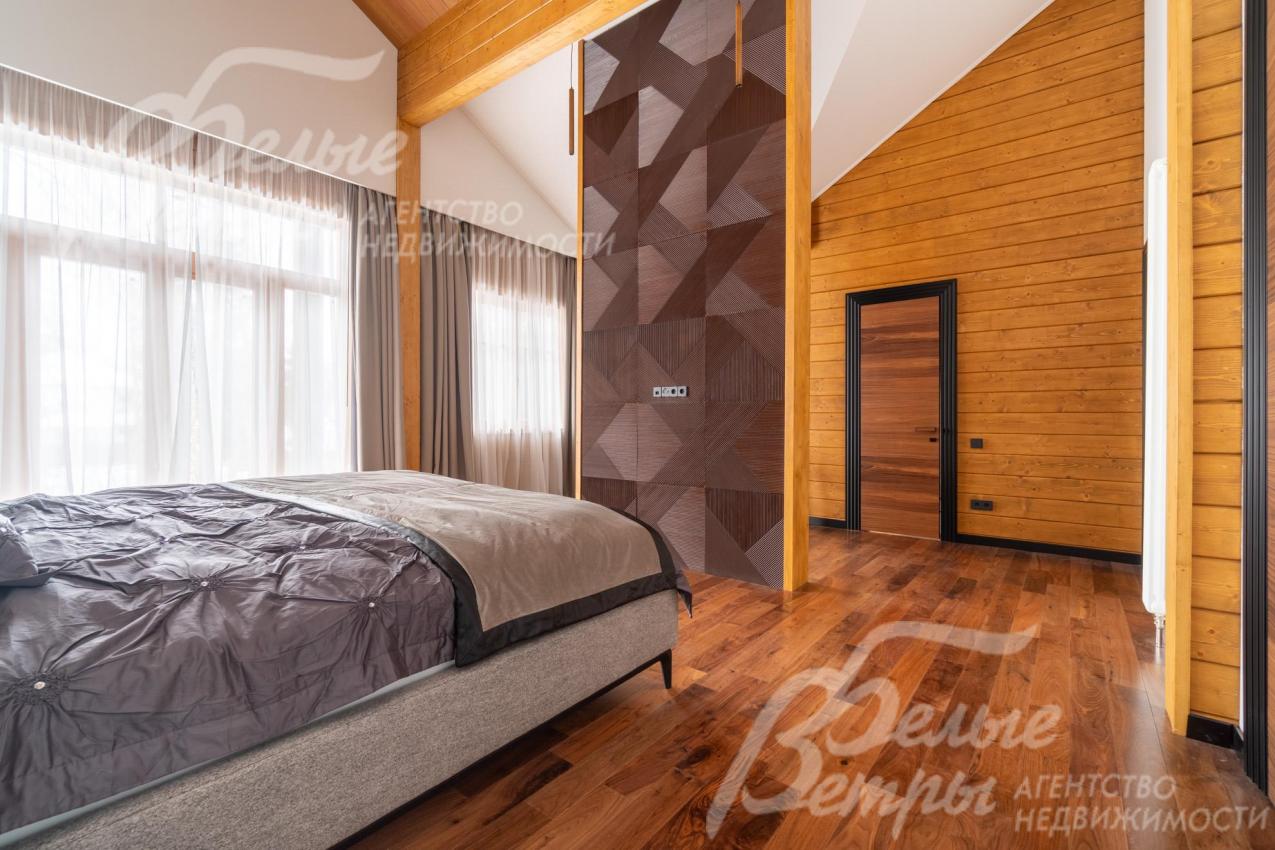 В мастер-спальне пространство визуально разделено на функциональные зоны с помощью декоративной стены-перегородки