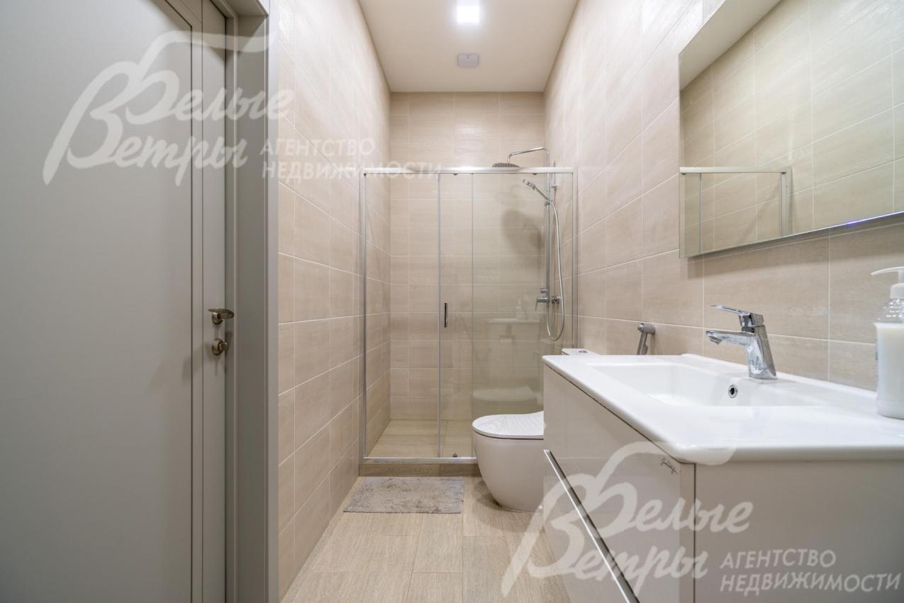 Санузел на первом этаже с душевой: стены от пола до потолка отделаны бежевым керамогранитом высшего сорта