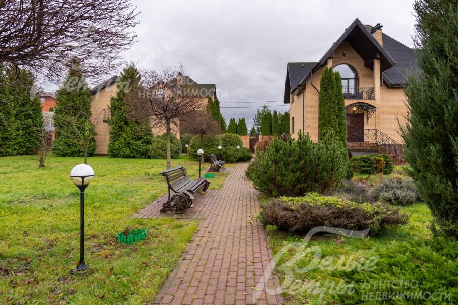 Дорожки выложены плиткой, вдоль них стоят скамейки и фонари