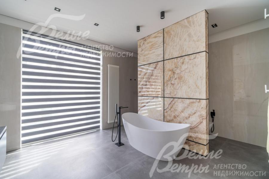 В санузел мастер-спальни - мраморная ванна с отдельно стоящим смесителем и стена из натурального оникса