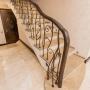 Лестница монолитная, отделана мрамором, с кованым ограждением и поручнем из дуба
