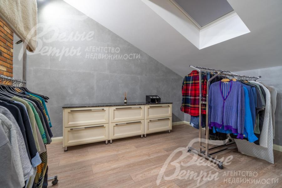 Гардеробная мастер-спальни с мансардным окном, оборудована системой хранения и рейлами