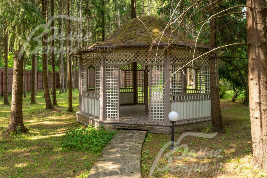 Еще одна изящная деревянная беседка в тени лесных деревьев.