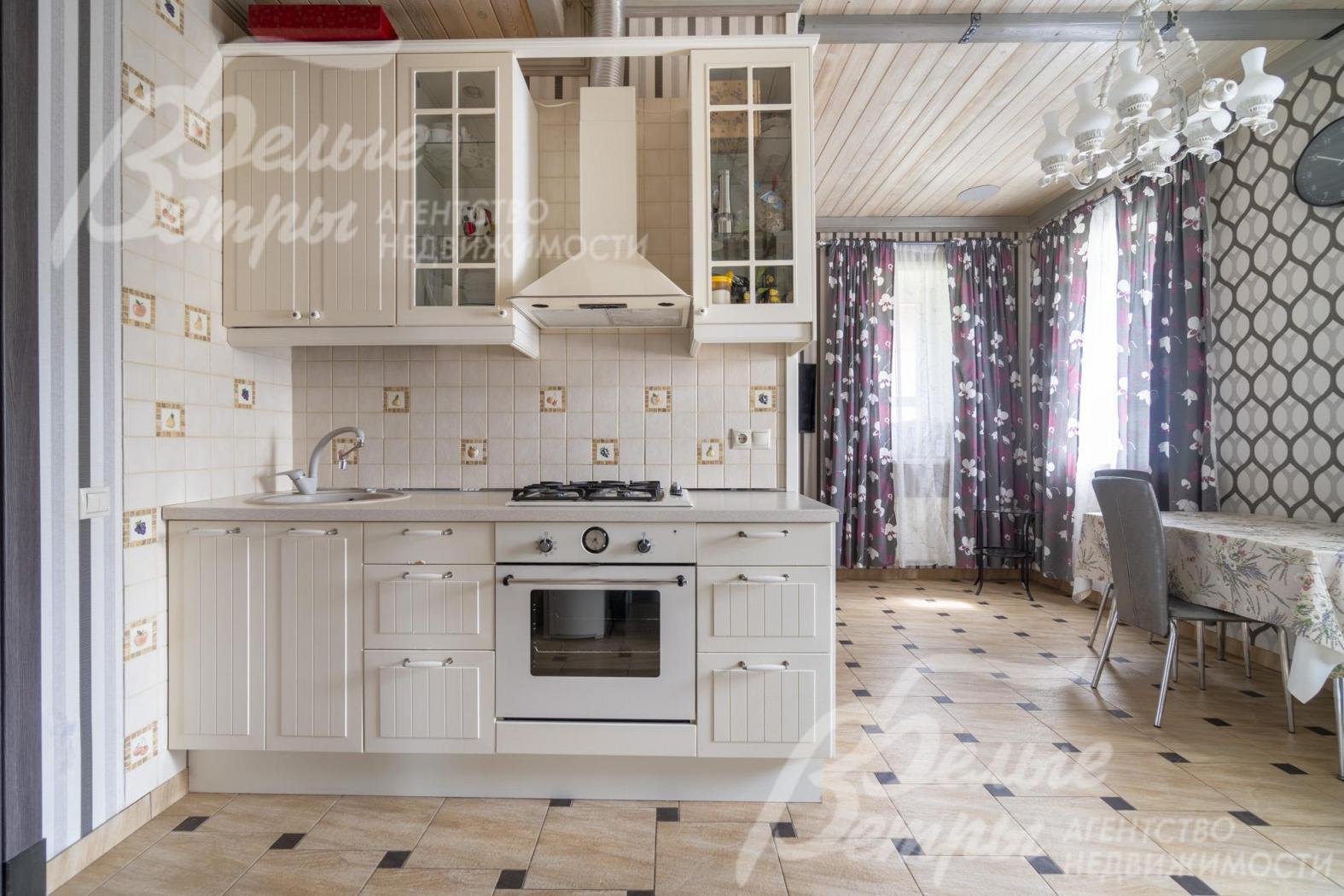 В кухне установлен белый кухонный гарнитур со всей необходимой техникой