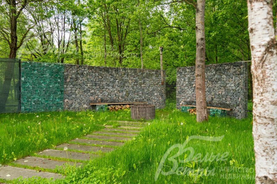В глубине участка — приватная зона отдыха с авторским оформлением: установлены габионы из камня и стекла, встроенные скамейки