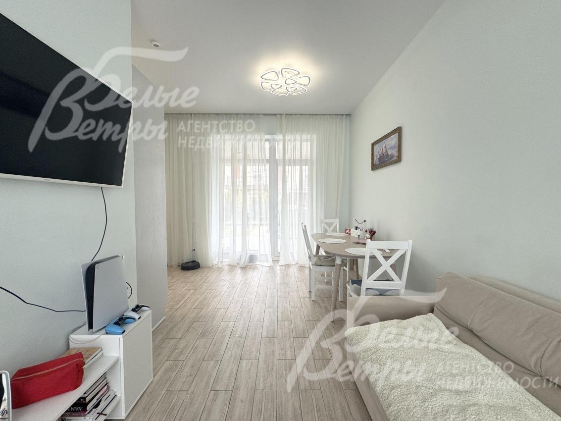 Зона кухни‑столовой плавно переходит в зону гостиной, где находится диван и телевизор