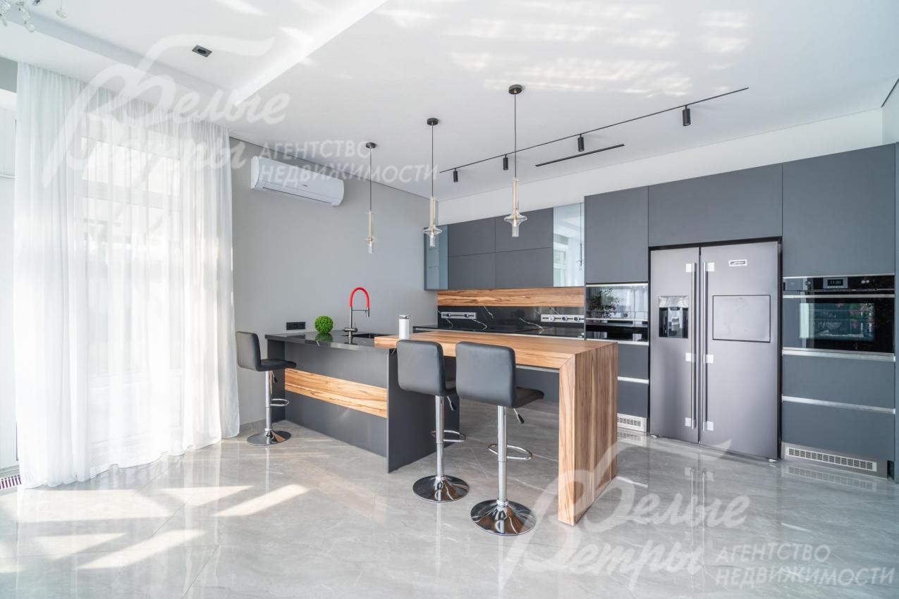 Кухня с функциональным островом-стойкой со шпонированной столешницей и барными стульями