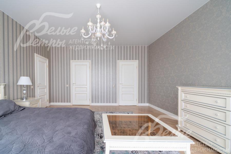 Мастер-спальня меблирована кроватью, прозрачным столиком и вместительным комодом