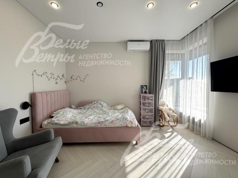 Одна из спален на втором этаже с кроватью, креслом, телевизором и окном углового типа