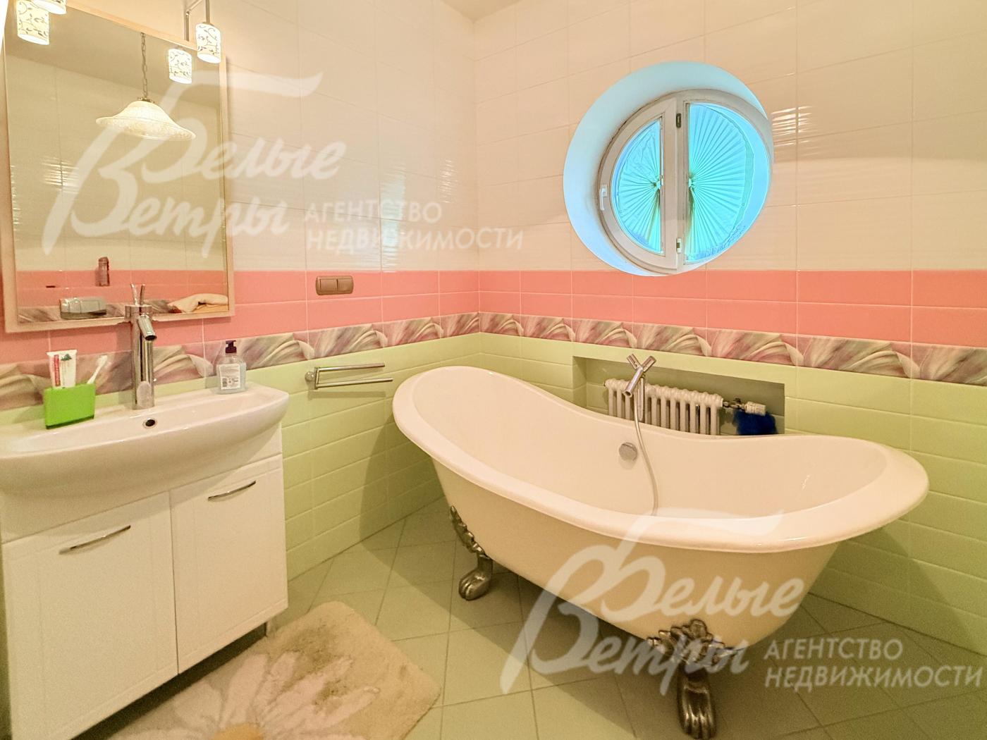 В санузле на втором этаже у окна стоит ванна овальной формы с декоративными ножками с бронзовой отделкой