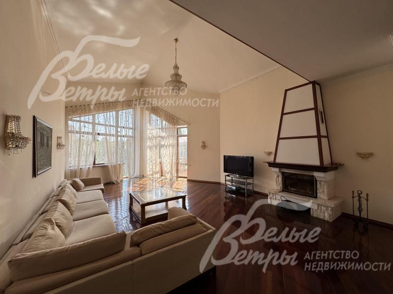 Атмосферу гостиной создают камин и стена с панорамным остеклением