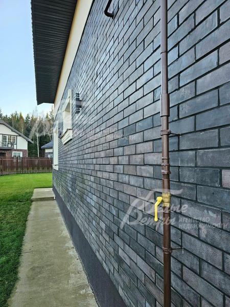 Стены 1го этажа облицованы термопанелями с темной плиткой под искусственный камень.