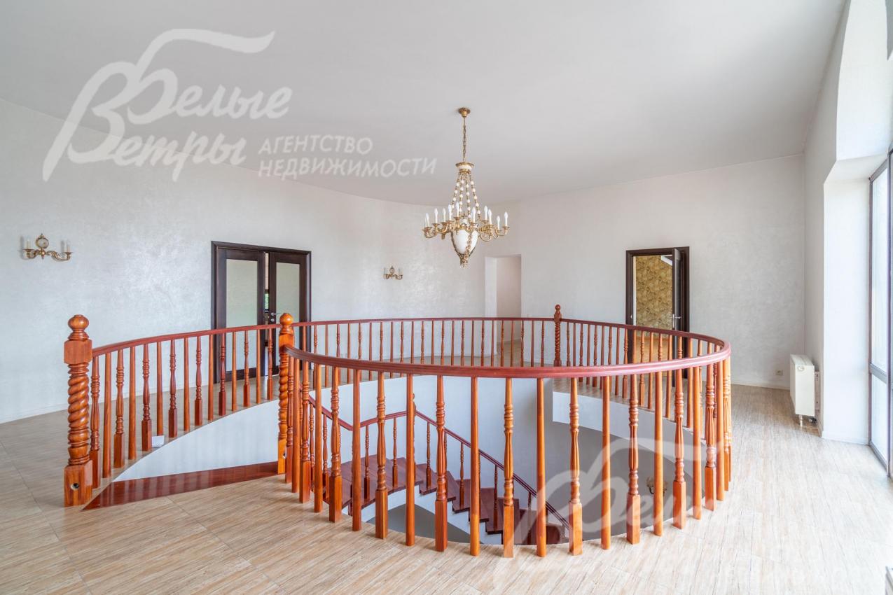 Холл второго этажа в светлых тонах с дубовыми лестничными перилами