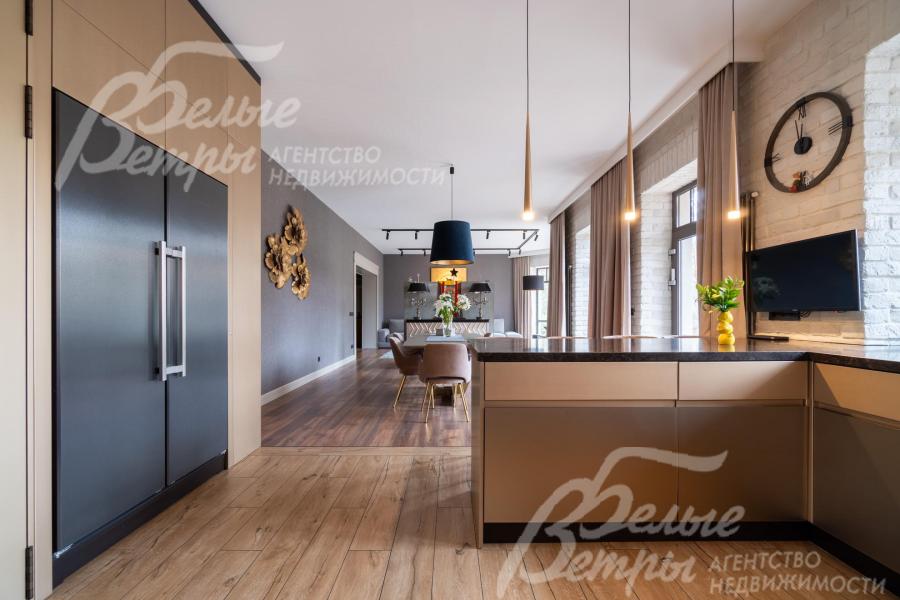 Кухня - с полубарным островом. Слева - выход в коридор. На кухне установлена встроенная техника брендов Neff, Bosch, Asko, плита Bertazzoni, холодильник и морозильник Liebherr