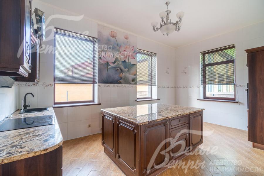 На кухне установлен гарнитур из дерева с островом и гранитными столешницами