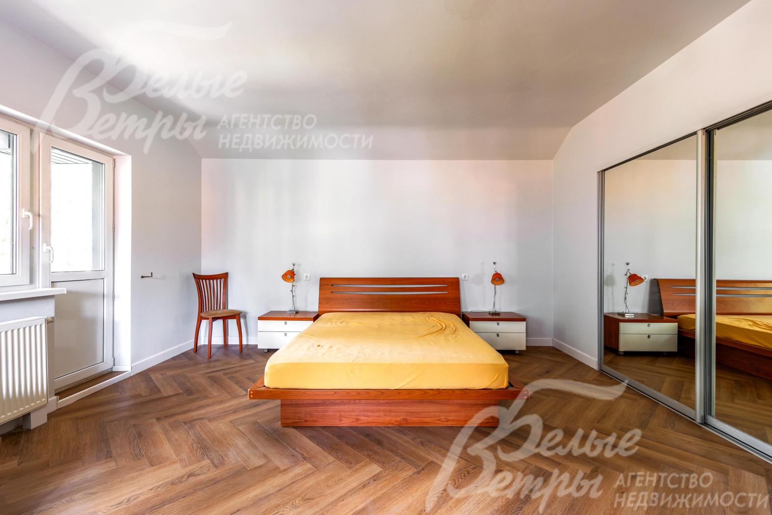 Одна из спален на втором этаже с кроватью и выходом на балкон