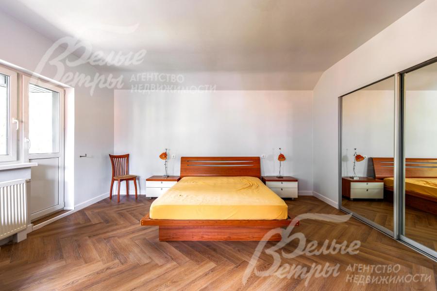 Одна из спален на втором этаже с кроватью и выходом на балкон