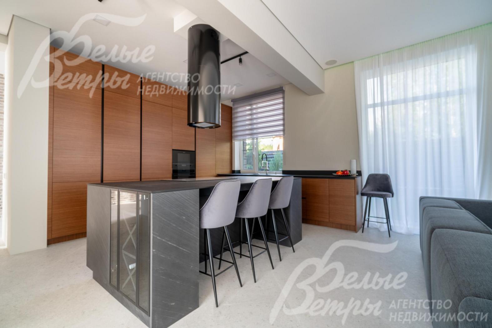 На кухне установлен гарнитур с фасадами из шпона ореха и остров с полубарным столом