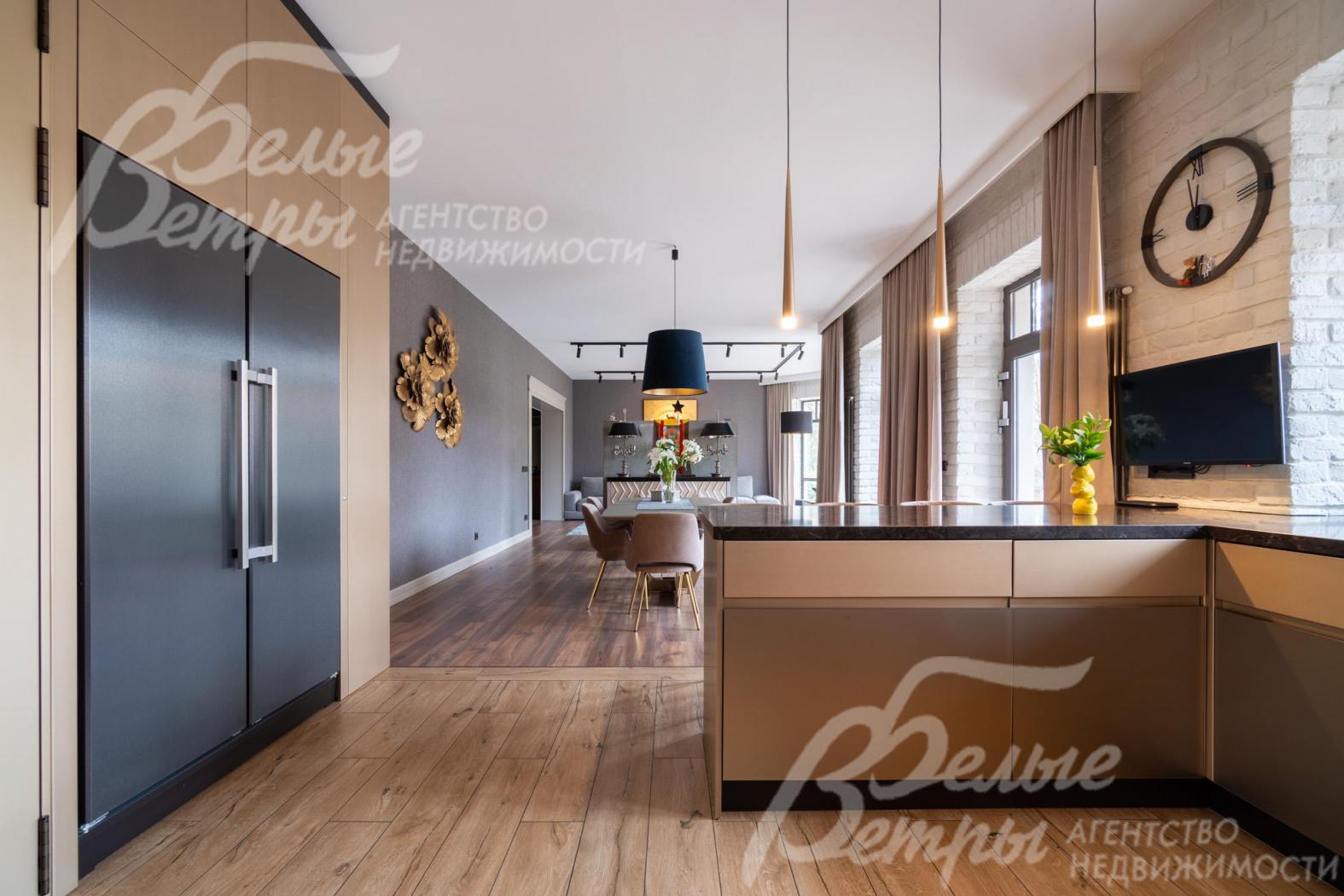 Кухня - с полубарным островом. Слева - выход в коридор. На кухне установлена встроенная техника брендов Neff, Bosch, Asko, плита Bertazzoni, холодильник и морозильник Liebherr