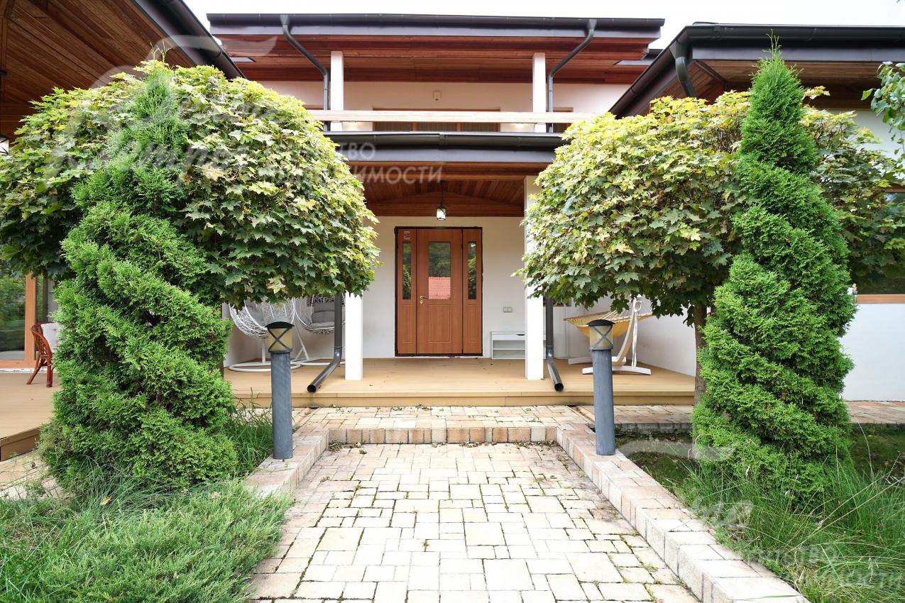 Главный вход в дом, украшенный декоративной подсветкой, клёнами и спиральными туями