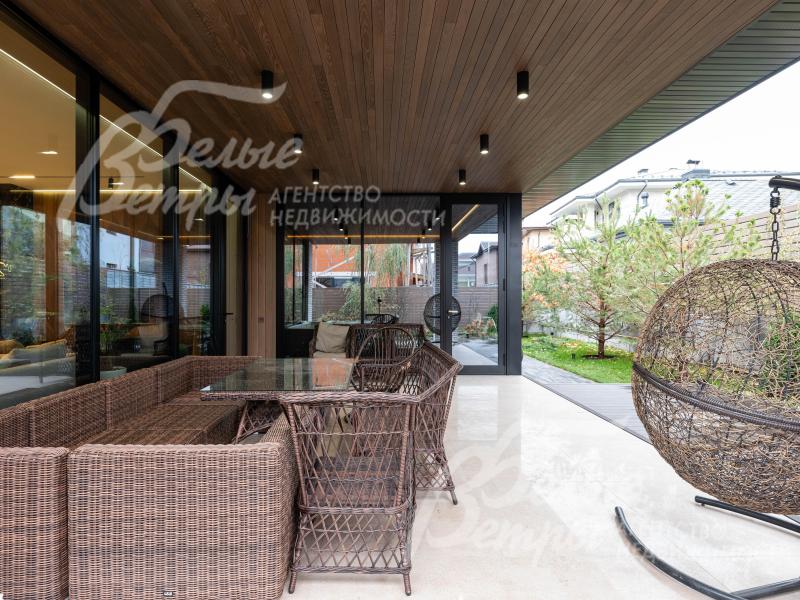 На террасе – мягкая мебель, освещенный столик, качели-кокон