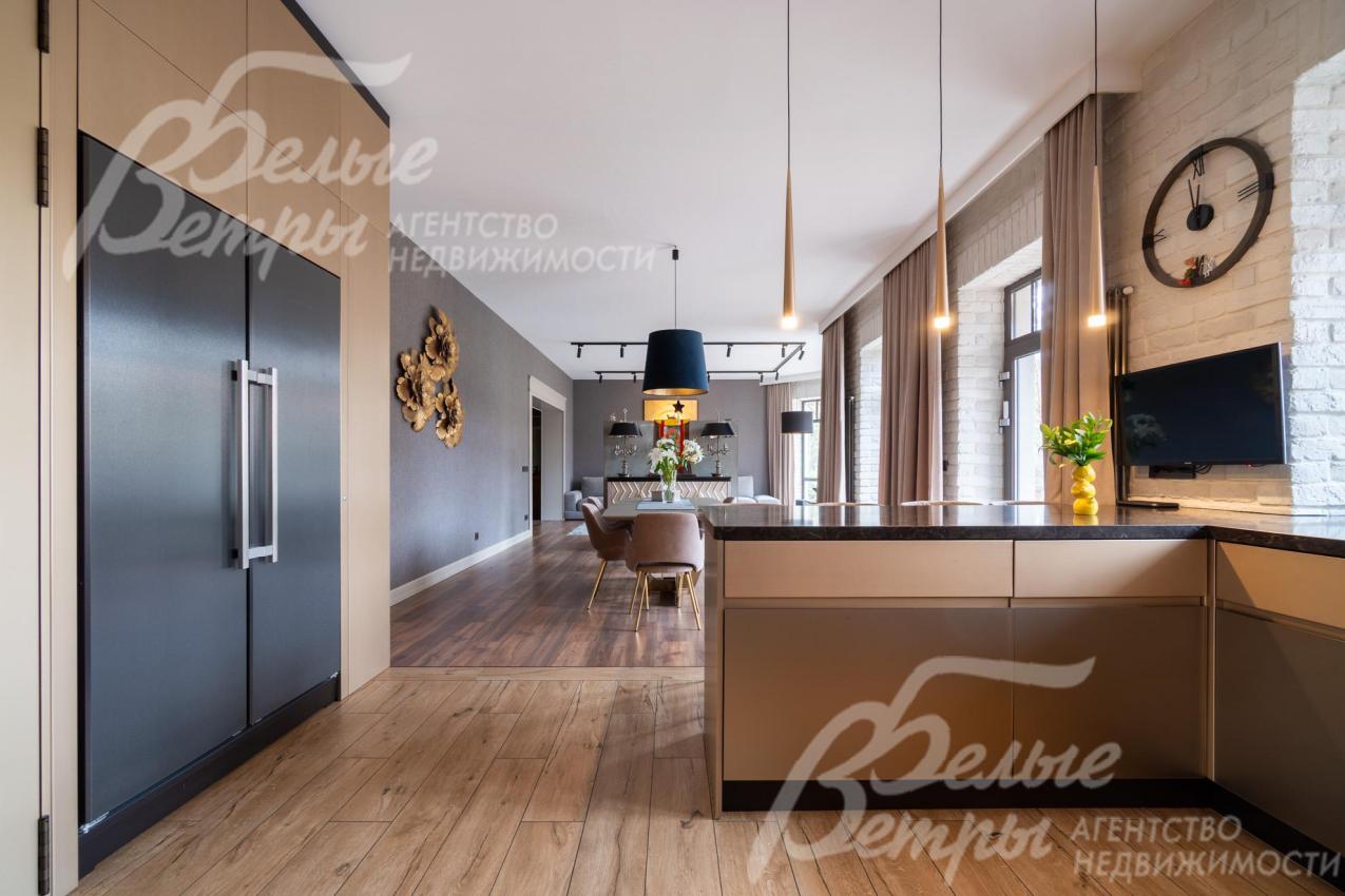 Кухня - с полубарным островом. Слева - выход в коридор. На кухне установлена встроенная техника брендов Neff, Bosch, Asko, плита Bertazzoni, холодильник и морозильник Liebherr