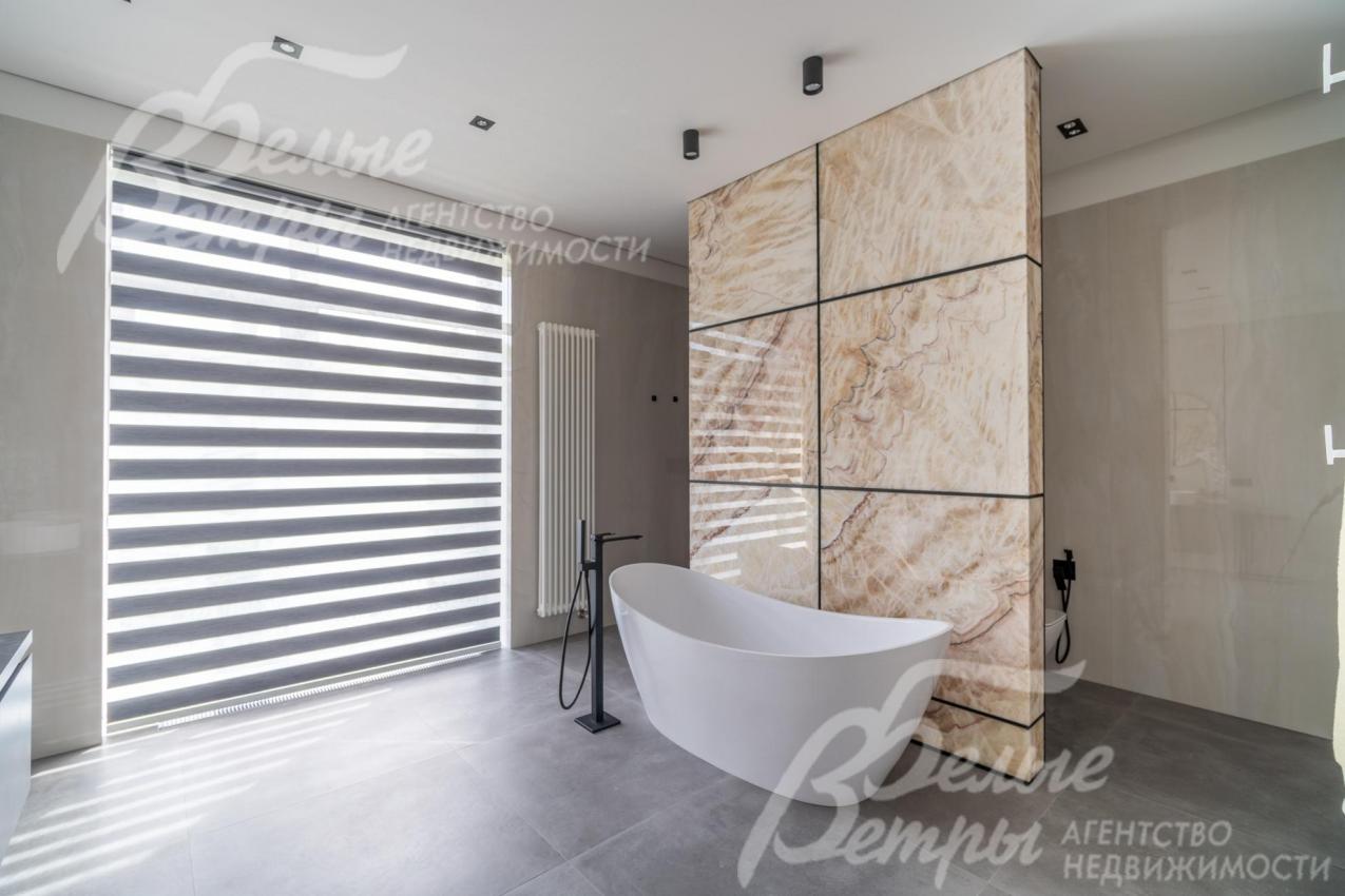 В санузел мастер-спальни - мраморная ванна с отдельно стоящим смесителем и стена из натурального оникса