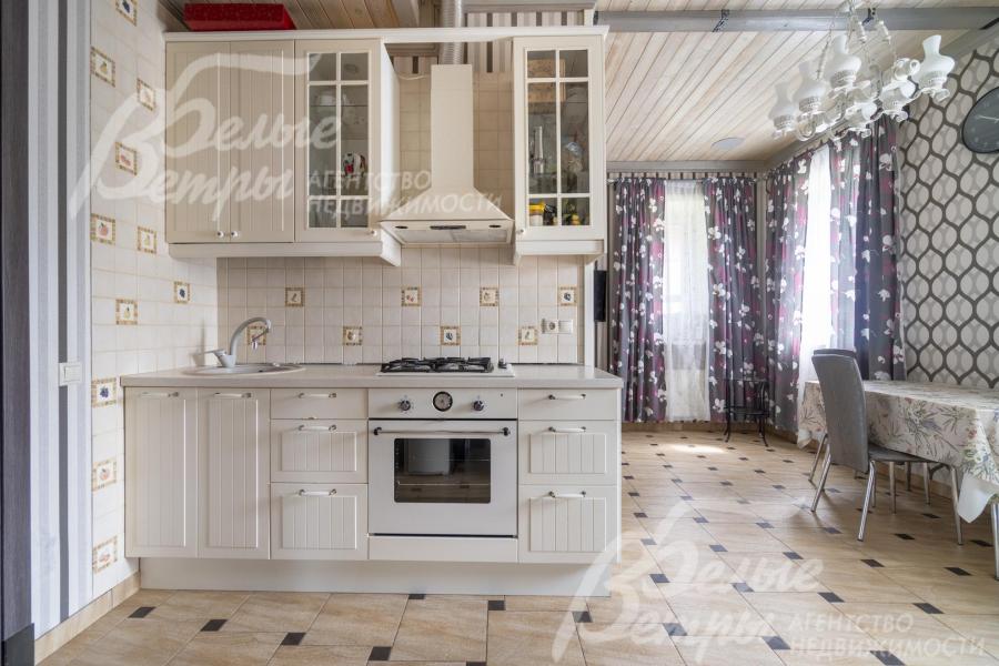В кухне установлен белый кухонный гарнитур со всей необходимой техникой