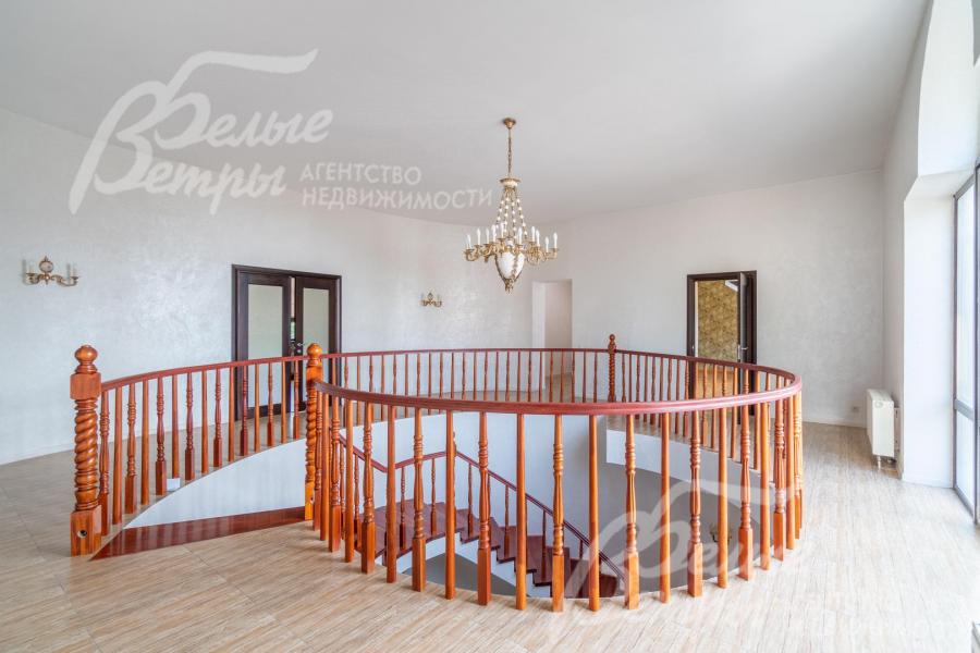 Холл второго этажа в светлых тонах с дубовыми лестничными перилами