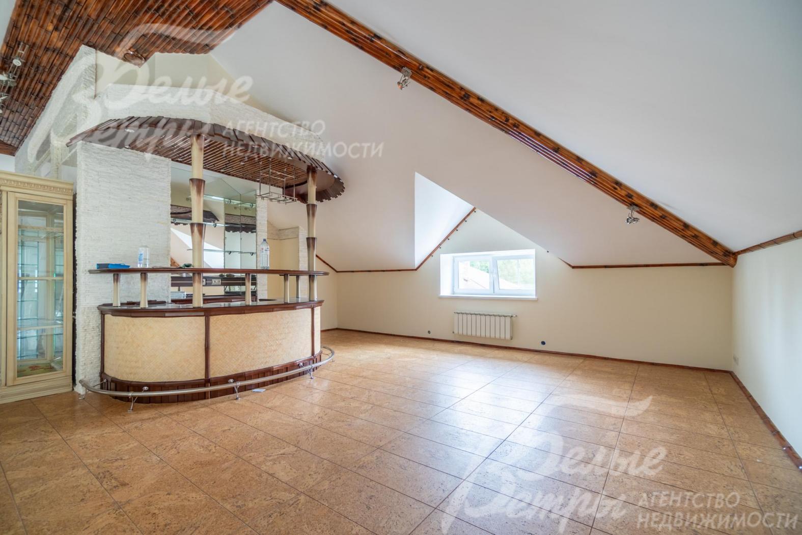 Холл на мансардном этаже с баром и шкафом со стеклянными дверцами