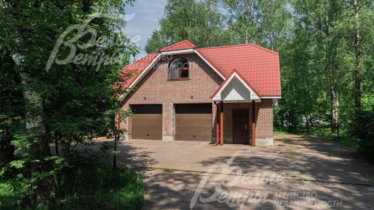 Вспомогательное 2-этажное строение в стиле основного дома с гаражом и квартирой для персонала, перед ним большая парковочная площадка 