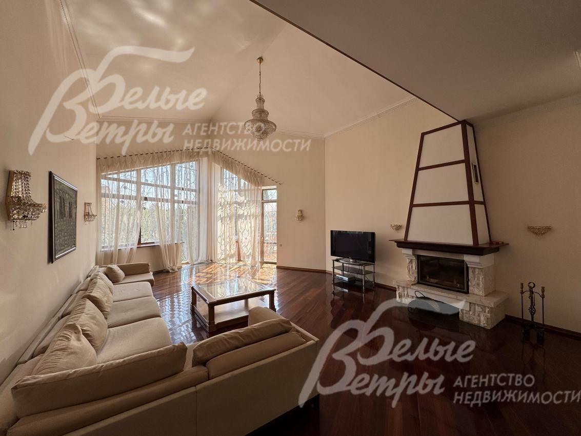 Атмосферу гостиной создают камин и стена с панорамным остеклением