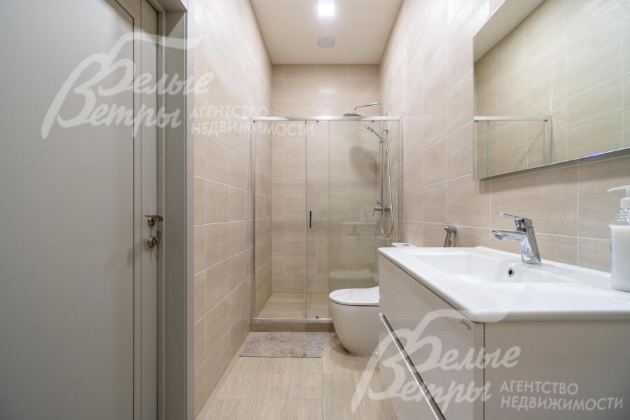 Санузел на первом этаже с душевой: стены от пола до потолка отделаны бежевым керамогранитом высшего сорта