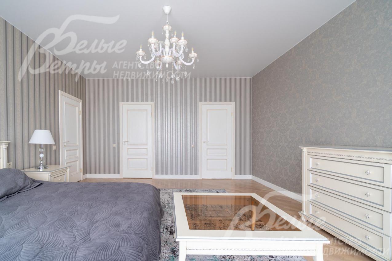 Мастер-спальня меблирована кроватью, прозрачным столиком и вместительным комодом